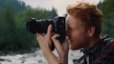 Fotoğraf makinesi kullanan bir fotoğrafçı. Dağlarda yürüyüş yaparken fotoğraf çeken bir adam.