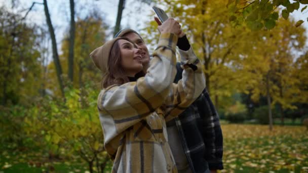 Vista de cerca de un par de amantes jóvenes disparando fotos de uno mismo en el teléfono inteligente . — Vídeos de Stock