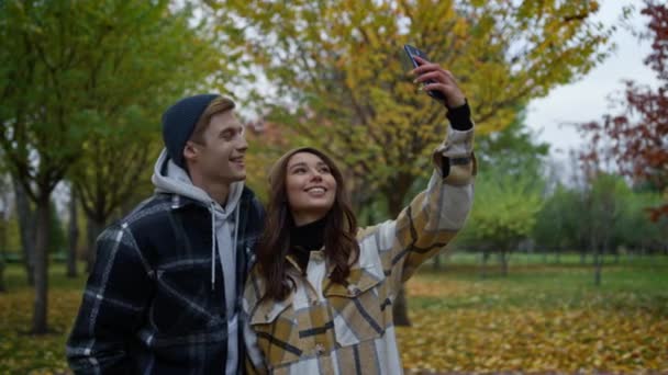 Cerca de amantes divertidos felices tomando selfie con el otoño de oro en el fondo. — Vídeo de stock