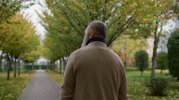 Close-up bekijk portret van volwassen man gaat door de herfst park. — Stockvideo