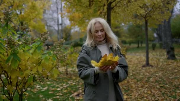 Κοντινό πλάνο όμορφη γυναίκα περπάτημα στο φθινοπωρινό πάρκο. Χαμογελαστή ηλικιωμένη κυρία. — Αρχείο Βίντεο
