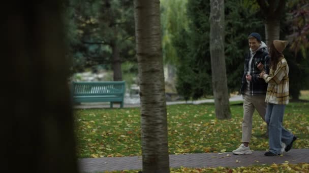 Usmívající se mladí milenci kráčející v krásném podzimním parku.Dívka a chlap chůzi . — Stock video