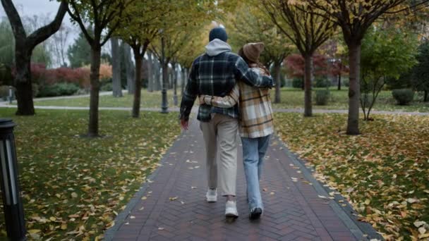 Szeroki widok młodych szczęśliwych kochanków spacerujących w jesiennym parku na pochmurną pogodę. — Wideo stockowe