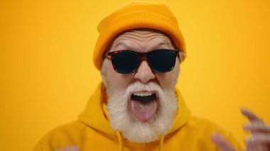 Yaşlı adam stüdyoda korkunç surat yapıyor. Kızgın olgun adam içeride el kol hareketi yapıyor..