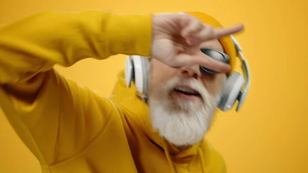 Smiling man relaxing in studio. Old guy listening music in headphones indoors. — Stock Photo, Image