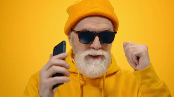 Hombre mayor escuchando música en el estudio. Chico alegre bailando con teléfono en el interior. — Foto de Stock