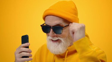 Olgun adam içeride dans ediyor. Telefonu olan neşeli yaşlı adam içeride eğleniyor..