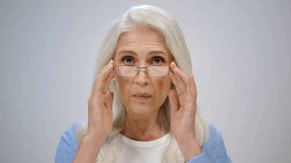 Mujer mayor estresada mirando la cámara interior. maduro señora fijación gafas dentro. — Foto de Stock