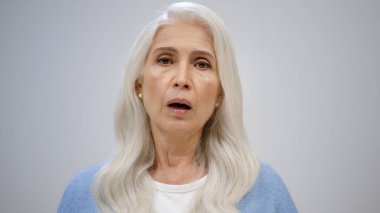 Hüsrana uğramış yaşlı kadın stüdyoda başını sallıyor. Evde el ele tutuşan üzgün bir kadın..