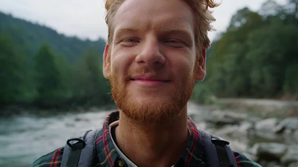 Man looking at camera outdoor. Tourist enjoying summer landscape in mountains