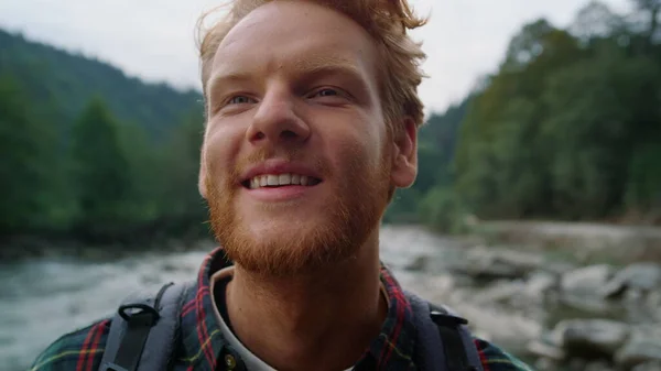 Hiker standing in mountain landscape. Redhead man looking at camera outdoor