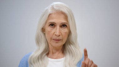 Stüdyoda poz veren yaşlı bir kadın. Olgun bir bayan evde jest yapmıyor..
