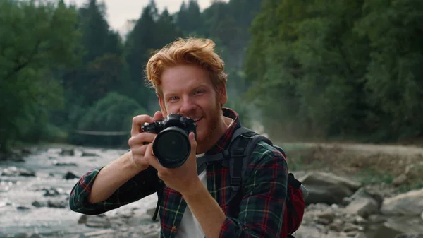 Χαρούμενος τύπος με κάμερα στο ποτάμι. Φωτογράφος τραβώντας φωτογραφίες στην κάμερα — Φωτογραφία Αρχείου