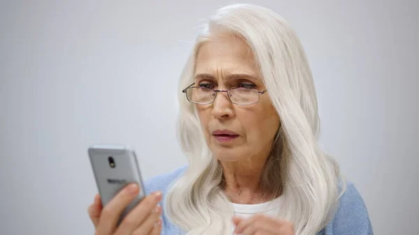 Una anciana seria mirando para protegerse dentro. Señora mayor fijación de gafas en el interior. — Foto de Stock