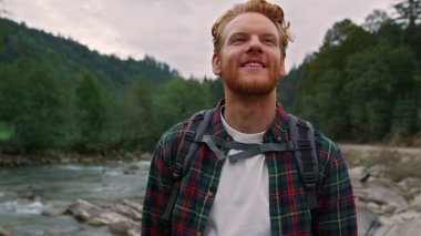 Yürüyüşçü dağ nehri boyunca yürüyor. Orman manzarasına bakan bir adam.