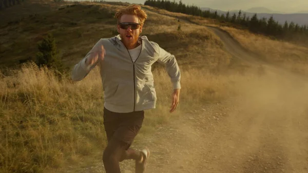 Ο κατάλληλος αθλητής τρέχει γρήγορα στο βρώμικο δρόμο. Αθλητικός άνθρωπος που τρέχει στα βουνά — Φωτογραφία Αρχείου