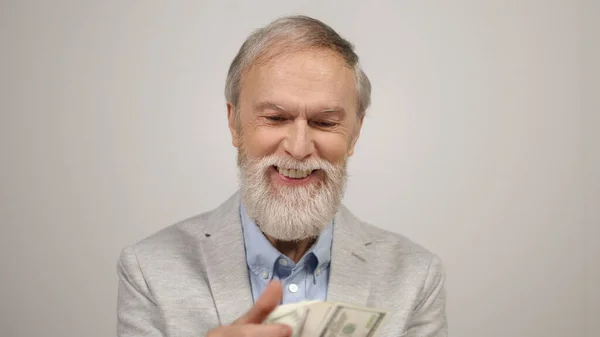 Mutlu yaşlı adam içeride para sayıyor. Modern stüdyoda dolarları elinde tutan zengin adam.. — Stok fotoğraf