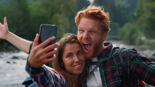 Homem e mulher a tirar selfie ao telefone. Amigos fazendo caras engraçadas na câmera — Fotografia de Stock