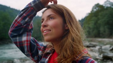 Dağlarda nehirde duran bir kadın. Kameraya bakan gülümseyen kızın portresi