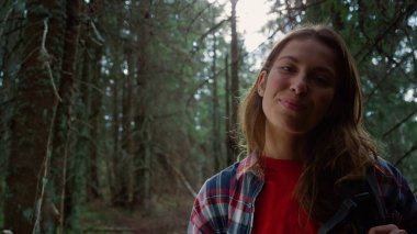 Ormanda kameraya poz veren neşeli kadın. Kadın yürüyüşçü başparmak işareti gösteriyor