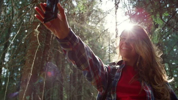 Reiziger neemt selfie op mobiele telefoon in het bos. Vrouw met tong op camera — Stockfoto