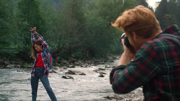 Мужчина с фотоаппаратом снимает девушку. Женщина позирует перед камерой на берегу реки — стоковое фото