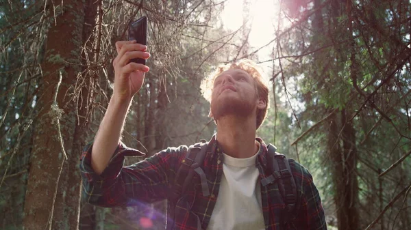 Hombre excursionista tratando de encontrar la red móvil en el bosque. Tipo sosteniendo smartphone — Foto de Stock