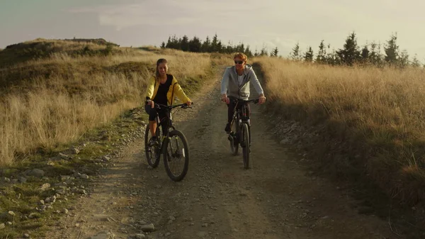 Пара їздить на спортивних велосипедах на дорозі. Щасливі велосипедисти тренуються в горах — стокове фото