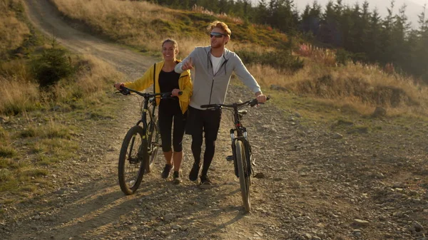 Uomo e donna che camminano sul sentiero con le biciclette. Amici che parlano durante la passeggiata — Foto Stock