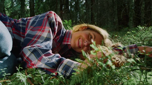 Meisje op groen gras in het bos. Vrolijke vrouw die varens aanraakt — Stockfoto