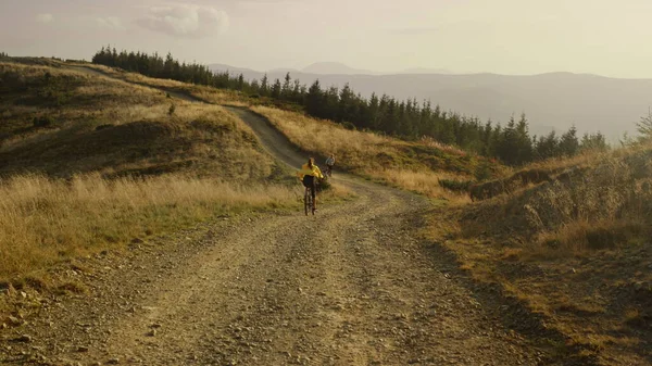 Жінка на велосипеді їде по гірській дорозі. Пара велосипедистів тренуються разом — стокове фото