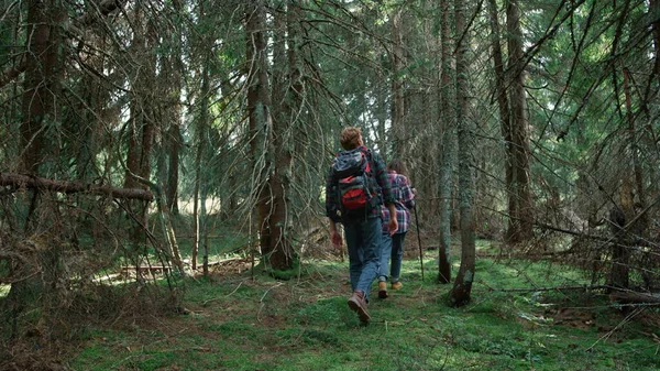 Usmívající se turisté procházející se v lese. Pár turistů na túrách mezi stromy — Stock fotografie