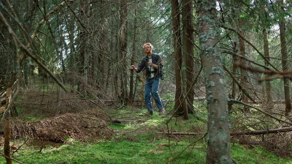 Uomo che cammina con bastoncini da trekking nel verde della foresta. Bello ragazzo trekking nel bosco — Foto Stock