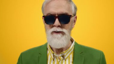 Gülümseyen yaşlı adam modern stüdyoda poz veriyor. Neşeli adam içeride iyi vakit geçiriyor..