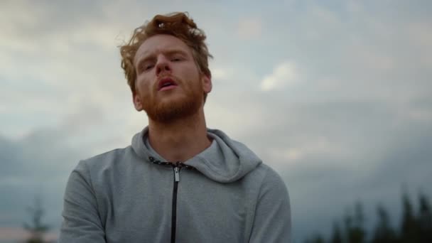 Sportsman posant à la caméra après l'entraînement. Athlète debout contre un ciel nuageux — Video