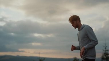 Erkek koşucu idmandan önce bacaklarını ısıtıyor. Aktif sporcu bacaklarını kaldırıyor.