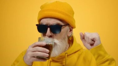 İçeride rahatlayan neşeli yaşlı bir adam. Stüdyoda alkol alan yaşlı bir adam..