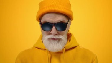 Stüdyoda gülümseyen neşeli yaşlı adam. Hipster yaşlı adam içeride yumruk kaldırıyor..