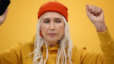 Evde telefonla müzik dinleyen yaşlı bir kadın. İçerde dans eden zarif bayan..