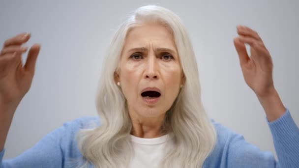 Geschokte senior vrouw huilend in de studio. Gestresste oude dame grijpt hoofd binnen. — Stockvideo