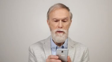 İçinde cep telefonu tutan gülümseyen adam. Evde telefona bakan yaşlı bir beyefendi..