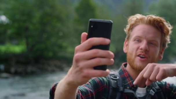 Ο τύπος χρησιμοποιεί smartphone για βιντεοκλήση. Συναισθηματική πεζοπόρος gesturing χέρι στην κάμερα — Αρχείο Βίντεο