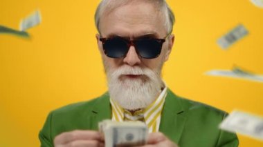 Para yağmuru altında kalan memnun yaşlı adam. Olgun adam içeride dolar sayıyor..