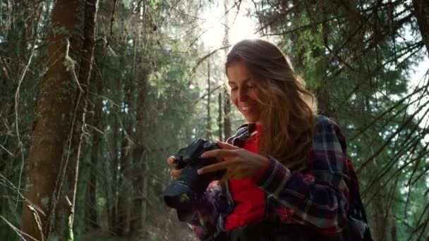 Flicka med fotokamera stående i skogen. kvinna som håller professionell kamera — Stockvideo