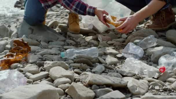 Dobrovolníci sbírají láhve na břehu řeky. Turisté čistí řeku od odpadků — Stock video