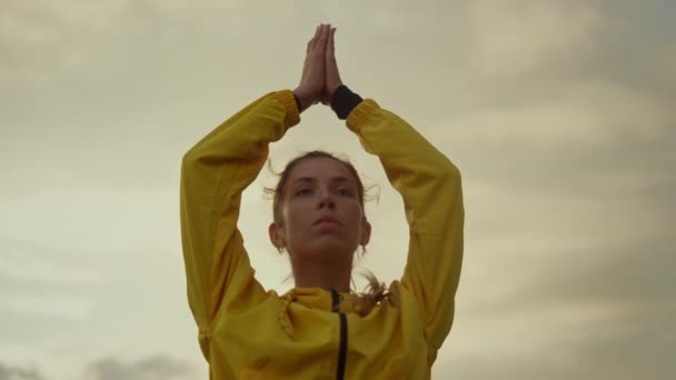 Chica enfocada haciendo yoga árbol pose. Mujer atractiva cogida de la mano por encima de la cabeza — Vídeos de Stock