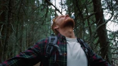 Ormanda duran erkek turist. Yürüyüş sırasında gülen adam ormanda dinleniyor.