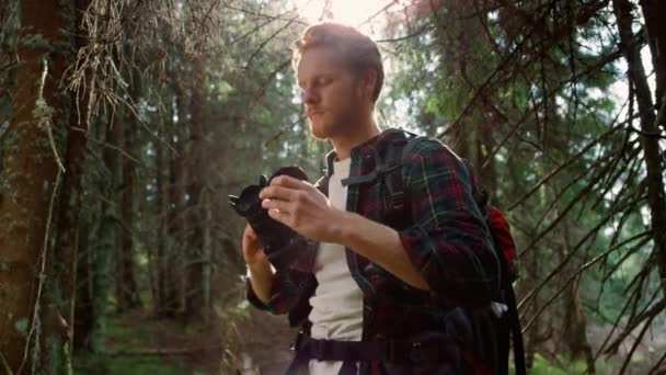 Fotograf mit Fotokamera steht im Wald. Wanderer fotografiert mit Kamera — Stockvideo