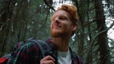 Yeşil ormanda duran bir adam. Sırt çantalı erkek turist ormanda mola veriyor.