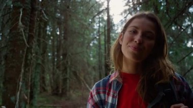 Ormanda kameraya poz veren neşeli kadın. Kadın yürüyüşçü başparmak işareti gösteriyor